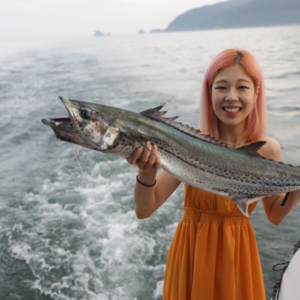 ヨットの上で釣った魚を持つお客様